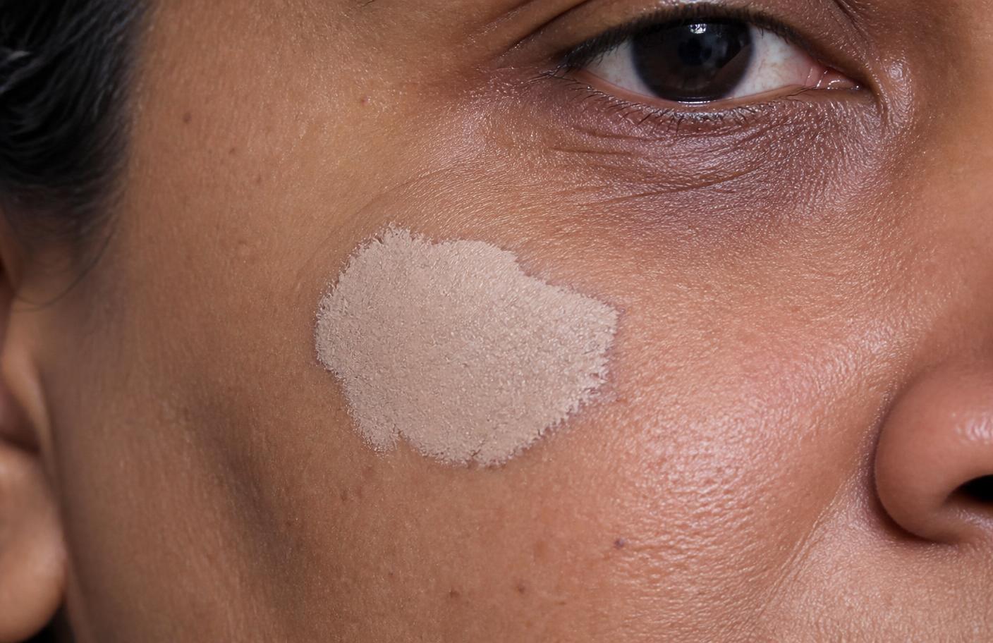 Chalky pale flesh-tone tattoo pigment sitting over a dark spot on deeper skin, reading ashy and mismatched